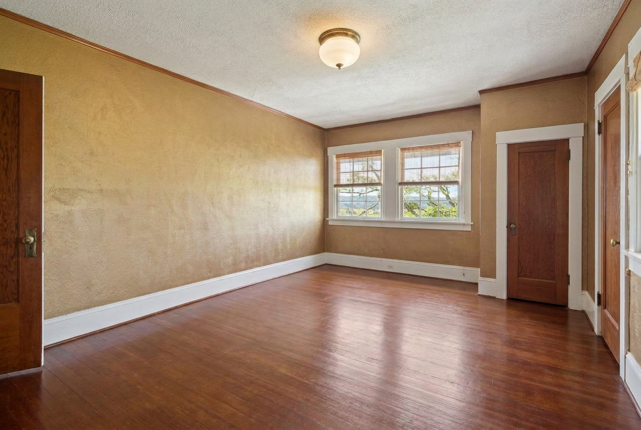 Corner bedroom with river-facing windows and hardwood floors, shown vacant